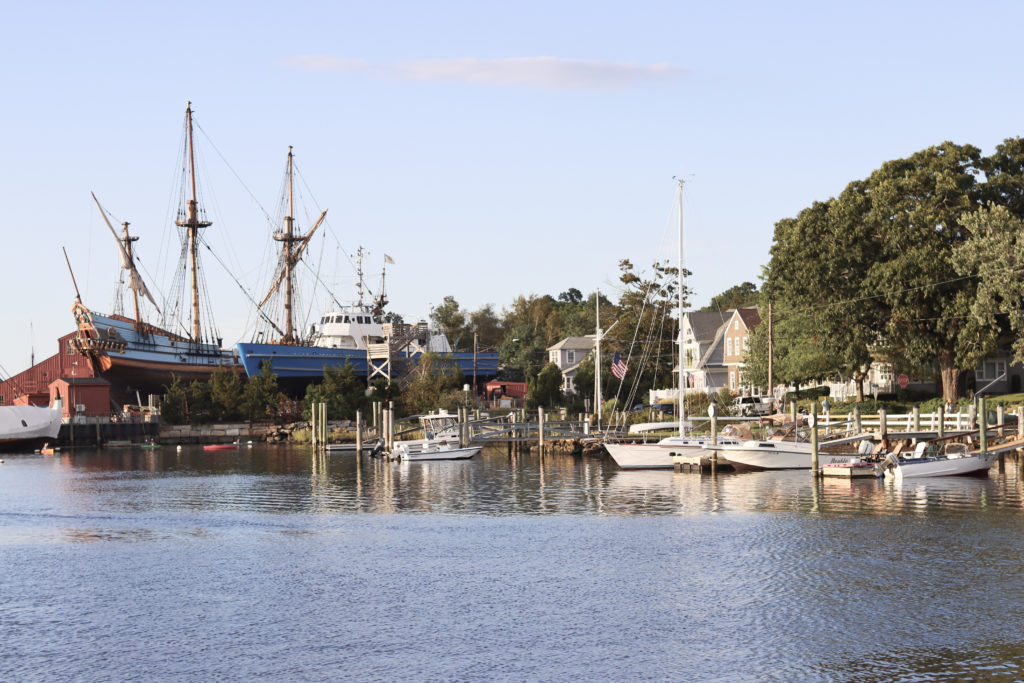 A river lined with historic ships in Mystic, a popular summer road trip destination