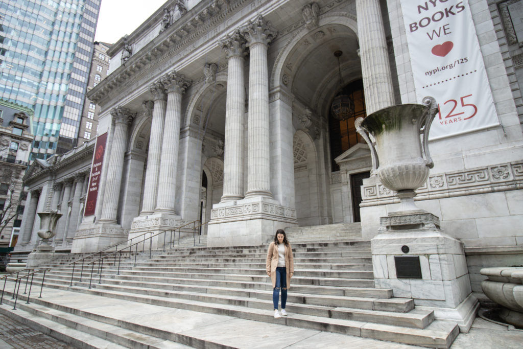 Woman standing in front of the New York Public Library, one of the Instagram spots in NYC