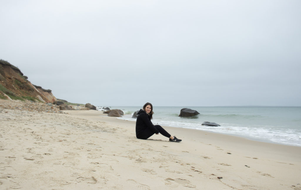 A women sitting on a sandy shore of one of the Martha's Vineyard beaches