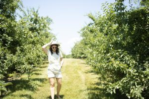 Woman standing in an orchard at Angry Orchard