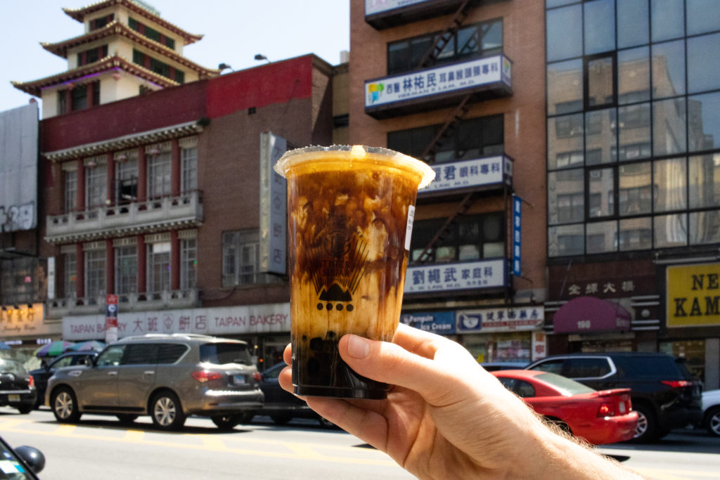 Bubble tea being held in front of Canal Street, one of NYC Coffee Shops 