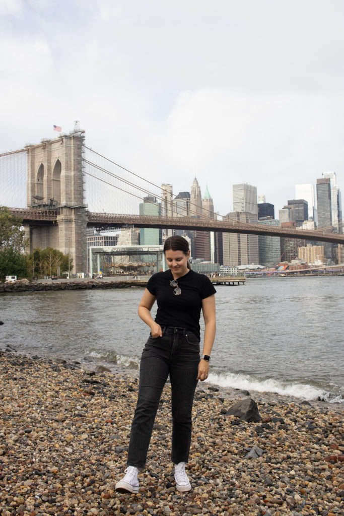 A women standing at Pebble Beach in Dumbo Brooklyn with the Manhattan skyline in the background