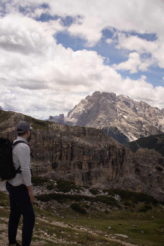 A man looking out at a mountain range found when hiking the Dolomites