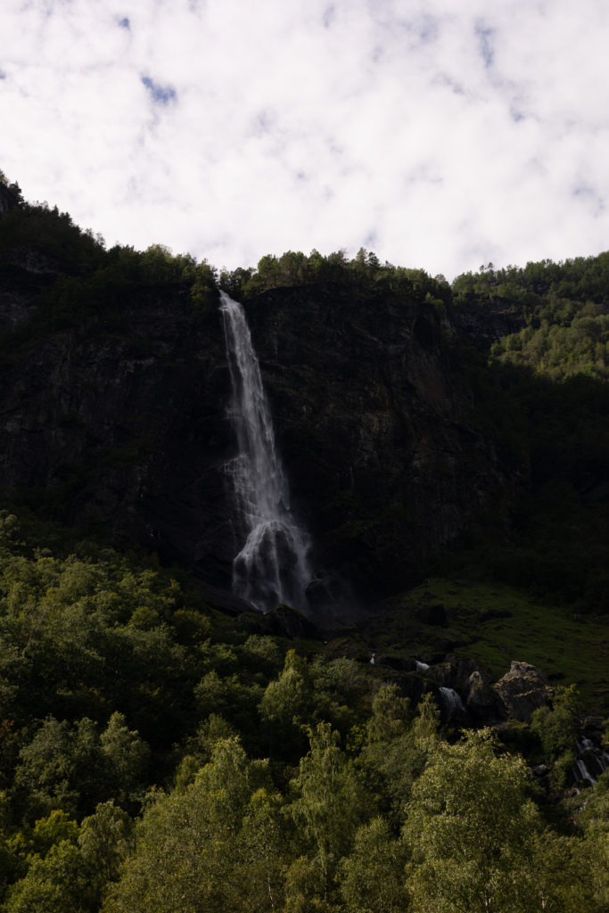 A large waterfall cascading down the side of a green mountain in Flåm Norway