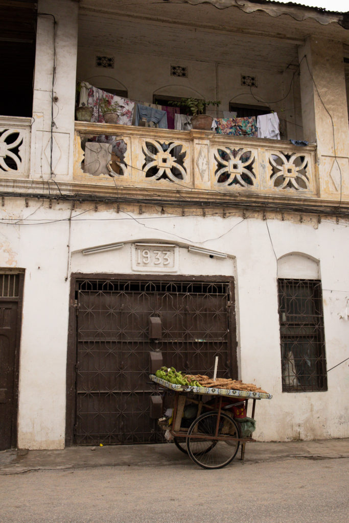 A view of a fruit cart outside of a white washed building in Stone Town, Zanzibar.