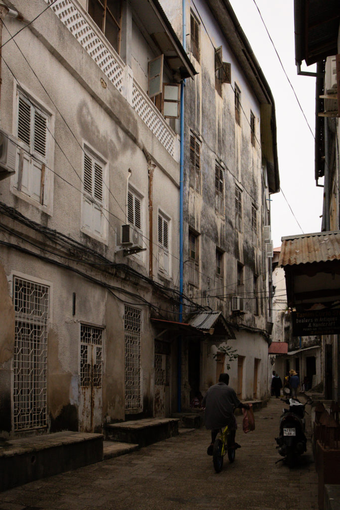 Photo of a winding street in Stone Town with a man biking away